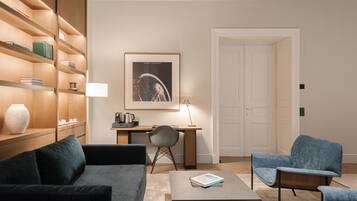 A modern living room with a sofa, two armchairs, a coffee table, a desk with a chair, a bookshelf, and a framed picture on the wall.