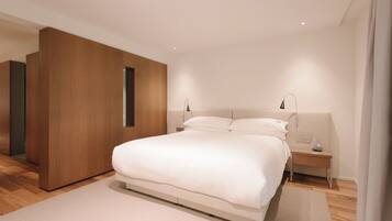 A modern bedroom with a large bed, wooden paneling, and bedside lamps.