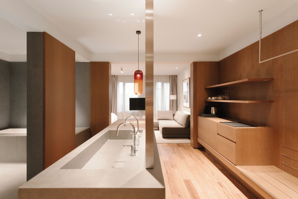 A modern bathroom with a central sink, a shower area, and a wooden vanity.