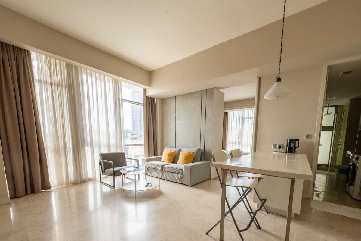 Un grand espace de vie comprenant un canapé, une table à manger et une cuisine située à l’arrière-plan.