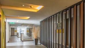 A hotel corridor with a staircase, a reception area, and a potted plant. - The Signature - Serviced residence (Kuala Lumpur)