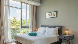 A hotel room with a large window, a bed with white linens, a nightstand with a lamp, and a framed picture on the wall. - The Signature - Serviced residence (Kuala Lumpur)