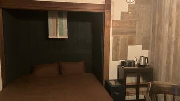 Un dormitorio con una cama grande, una mesita de noche con hervidor y una silla.