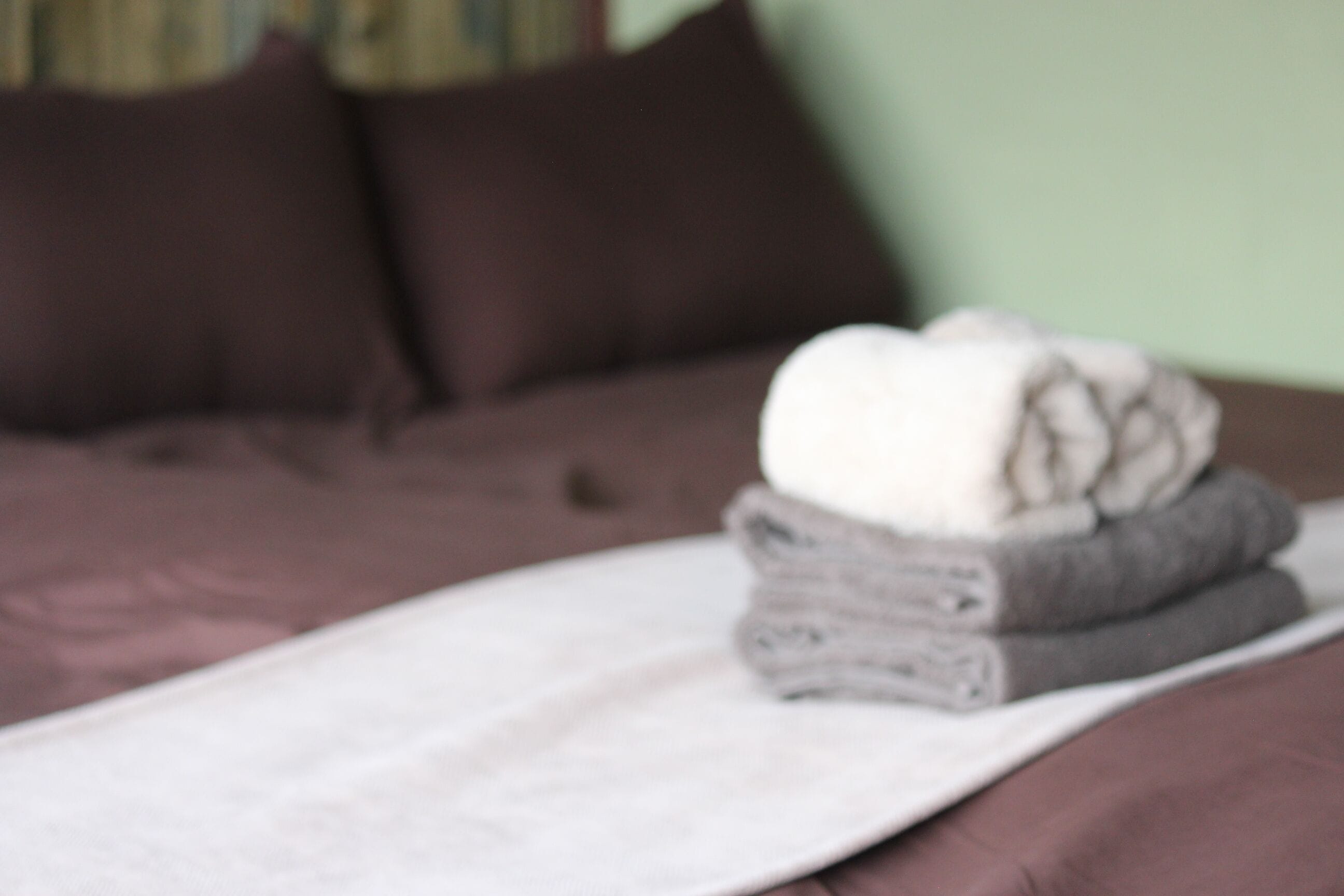 A bed with a white blanket and folded towels.