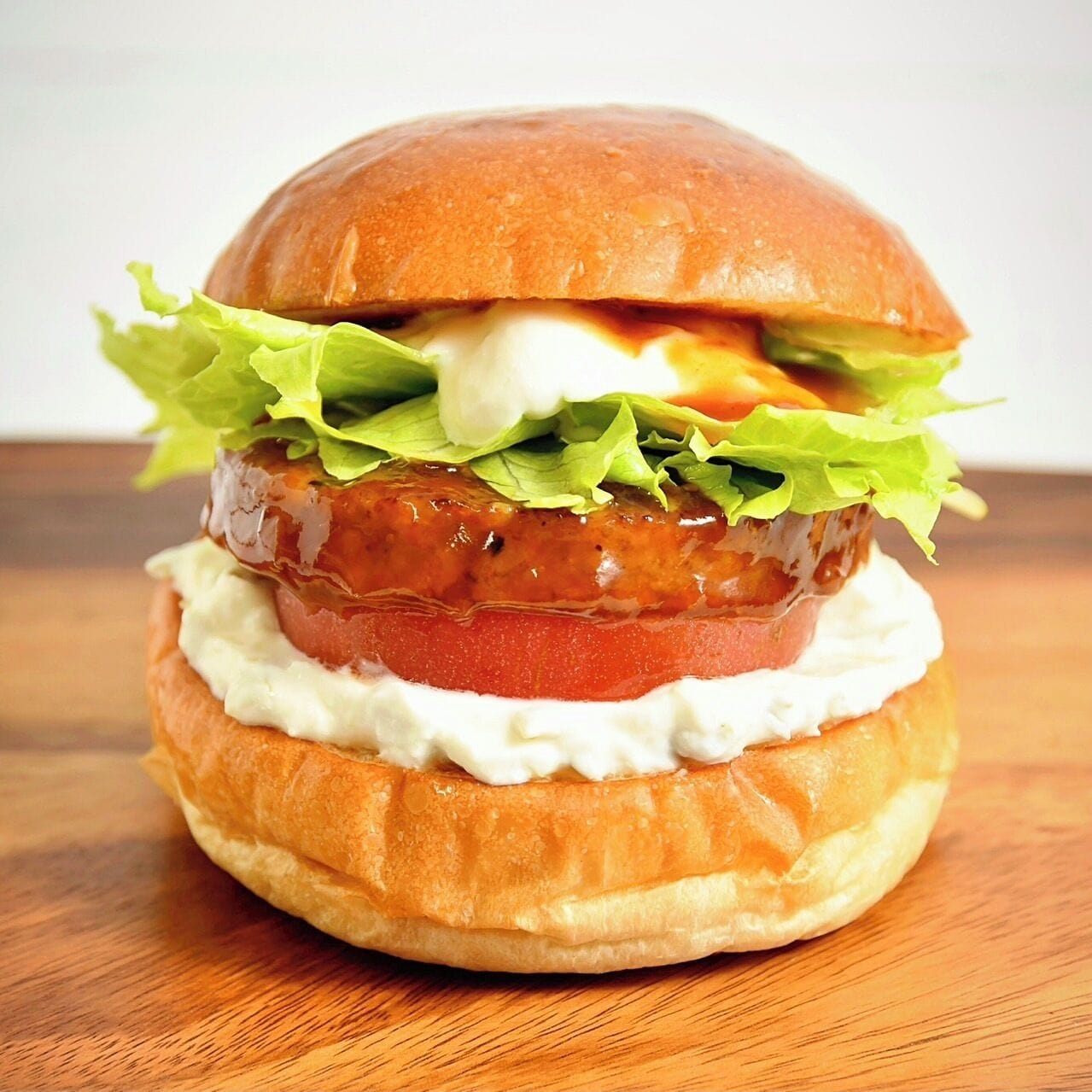 Hambúrguer com alface, tomate e molho no pão.