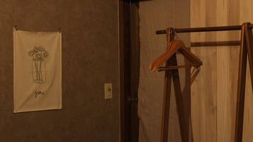 A room with a wooden door, a towel hanging on the wall, and a wooden hanger rod.