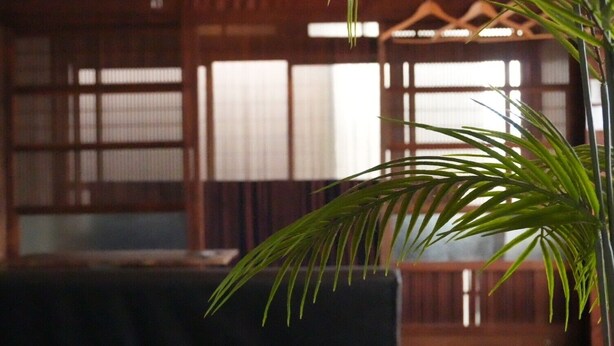 Una habitación con puertas correderas de madera tradicionales, una mesa oscura y una planta en maceta.