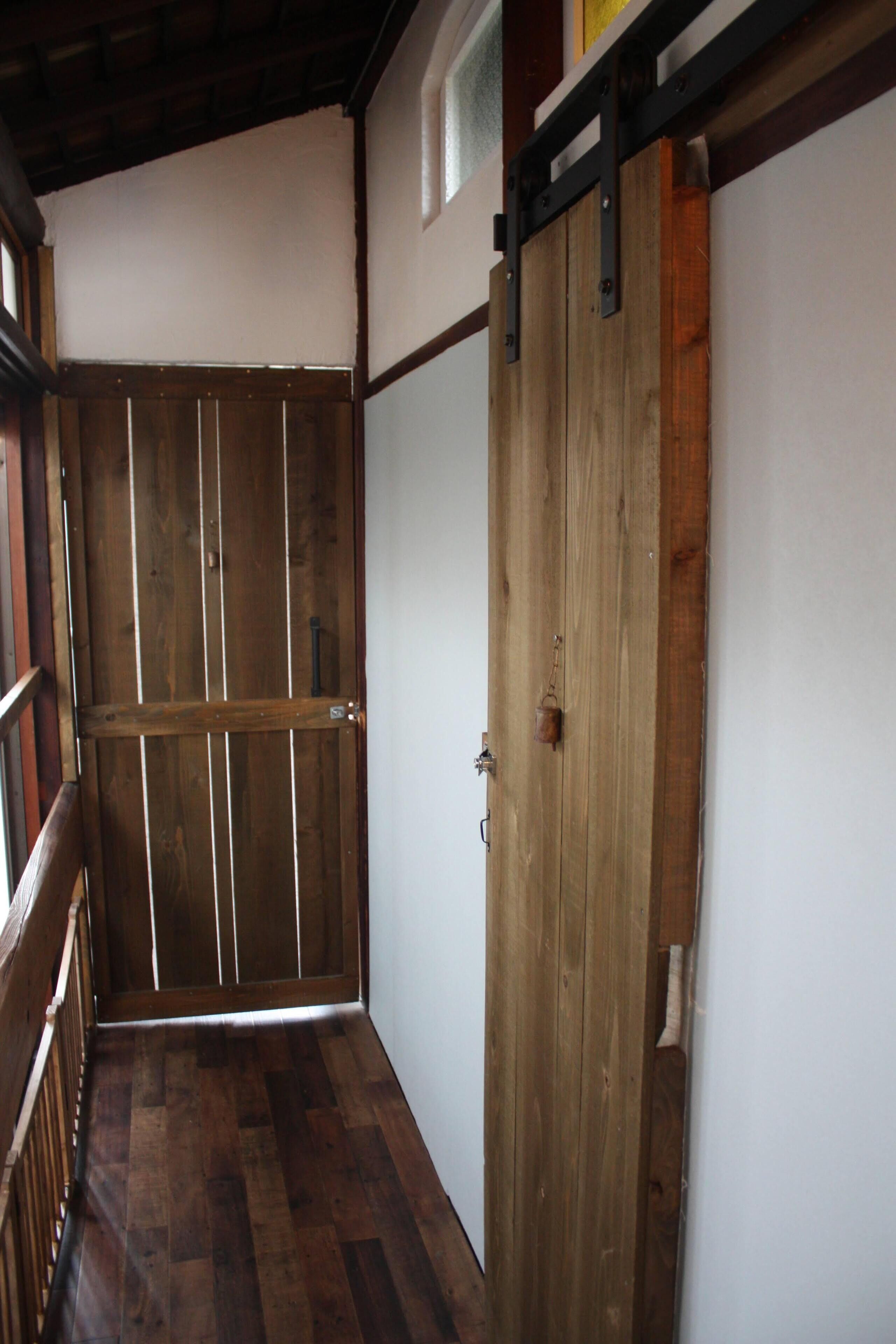 A hallway with wooden flooring and a large wooden door with a metal handle.