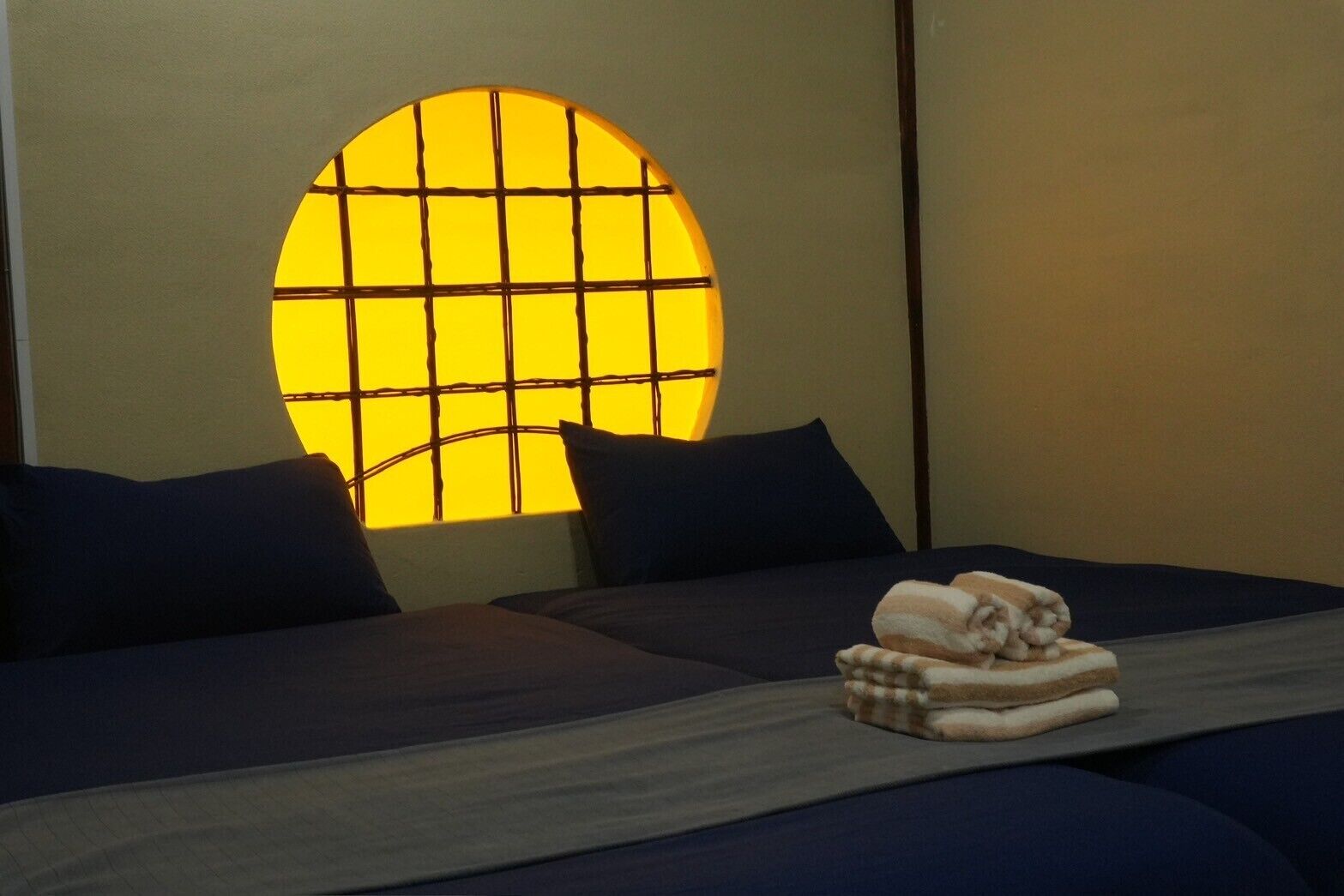 A room with a bed, a window with a grid pattern, and towels on the bed.