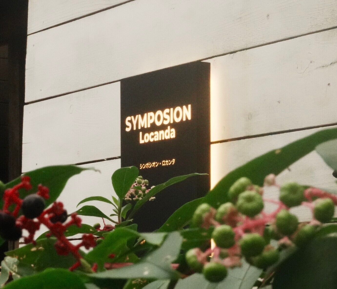 A sign for "SYMPOSION Locanda" with Japanese text.