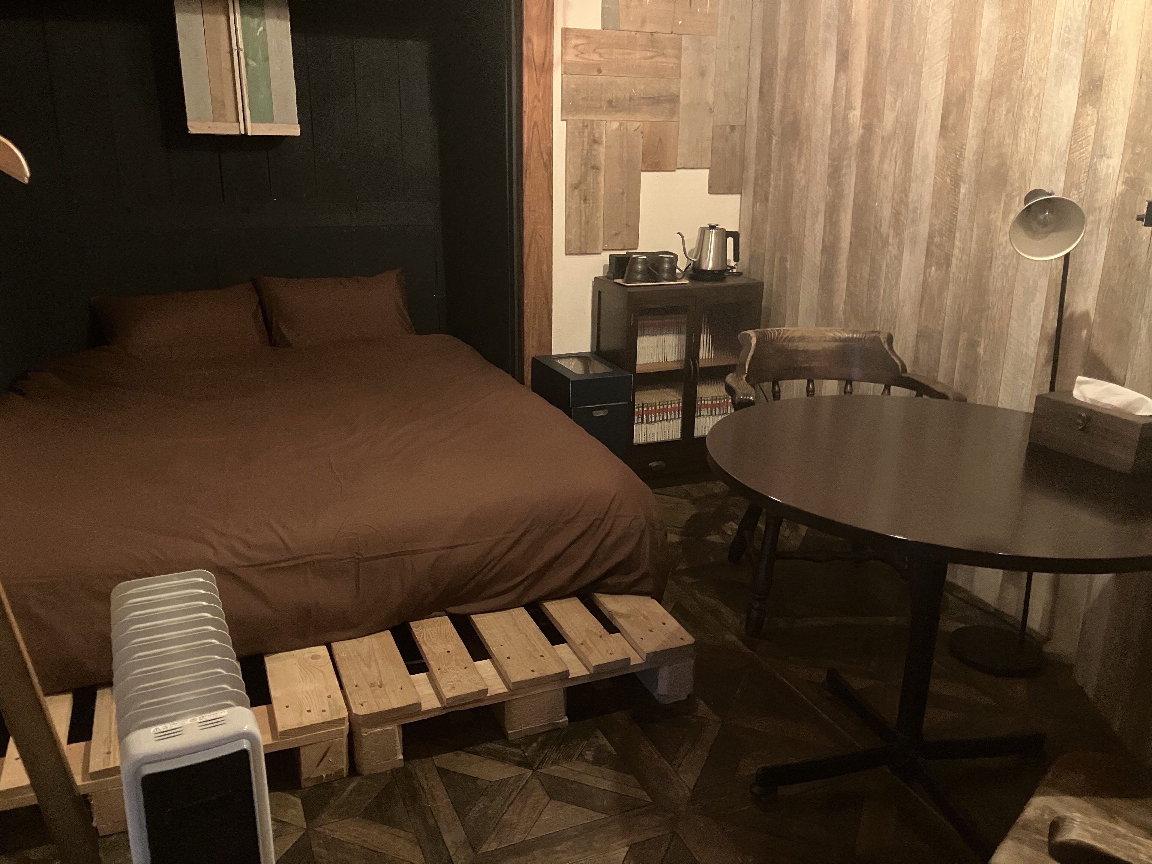 A cozy room with a large bed, a small table, a chair, and a unique wooden bench.