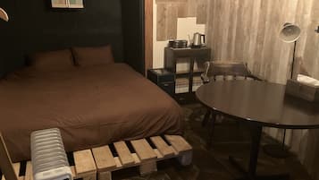 A cozy room with a large bed, a small table, a chair, and a unique wooden bench.