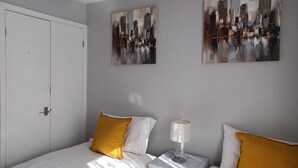 Une chambre à coucher avec un lit, une table de chevet, une lampe et deux tableaux accrochés au mur.