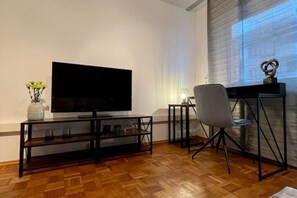 Relax in this stylish living room with a flat-screen TV, comfortable chair, and beautiful plants.