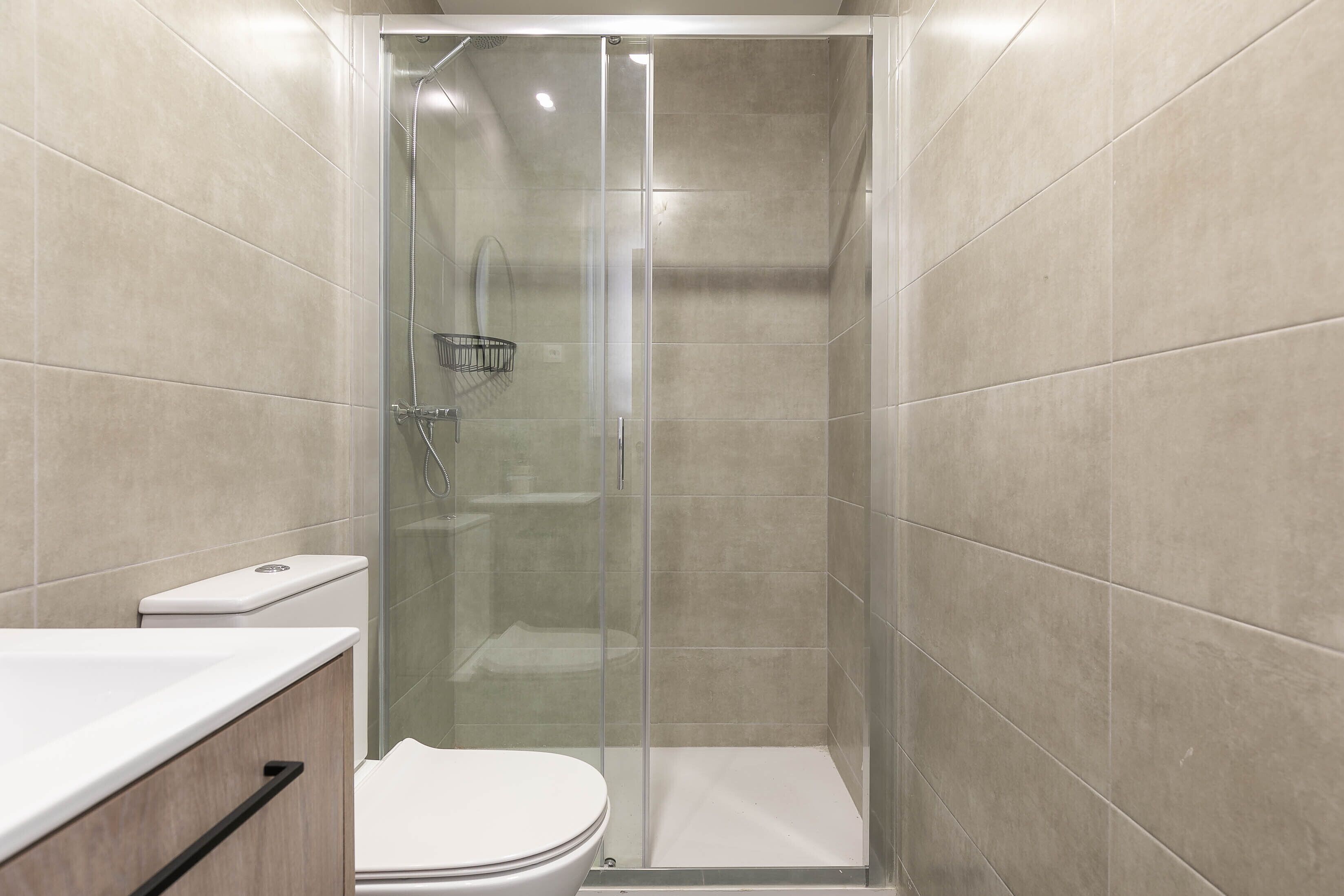 Un baño con ducha acristalada, inodoro y lavamanos.