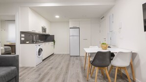 Une cuisine moderne équipée d’un lave-linge, d’un réfrigérateur et d’un coin repas avec une table et des chaises.