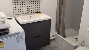 A bathroom with a white sink, mirror, and toilet. There is a shower curtain and a small shelf with a towel and a soap dish. - Studio Proche Centre ET Plage Avec Clim ET Parking (La Grande-Motte)