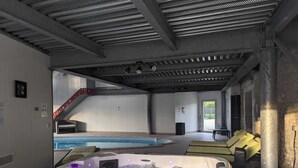 Ein Wellnessbereich mit Whirlpool, Schwimmbecken und einer Treppe zu einer erhöhten Ebene.