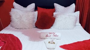 A neatly made bed with white and red bedding, a red throw blanket, and a white pillow with "WG Guest Villas" text. - WG Guest Villas  (Bulawayo)