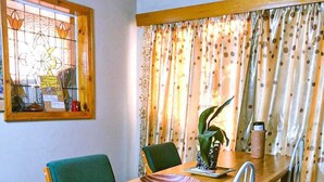 A dining area with a wooden table, green chairs, a bowl, and a potted plant. - WG Guest Villas  (Bulawayo)