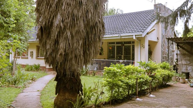 A house with a tiled roof, a stone wall, and a pathway leading to the entrance. - WG Guest Villas  (Bulawayo)