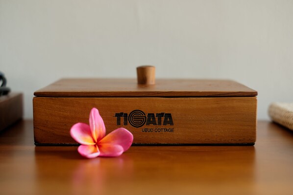Una caja de madera con la inscripción "TIGATA UBUD COTTAGE", sobre una superficie de madera.