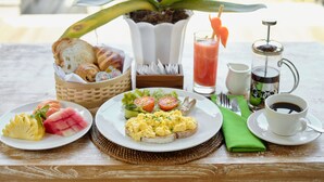 Frühstücksstillleben mit Croissants, Rührei, Wassermelone und einer Kaffeekanne.