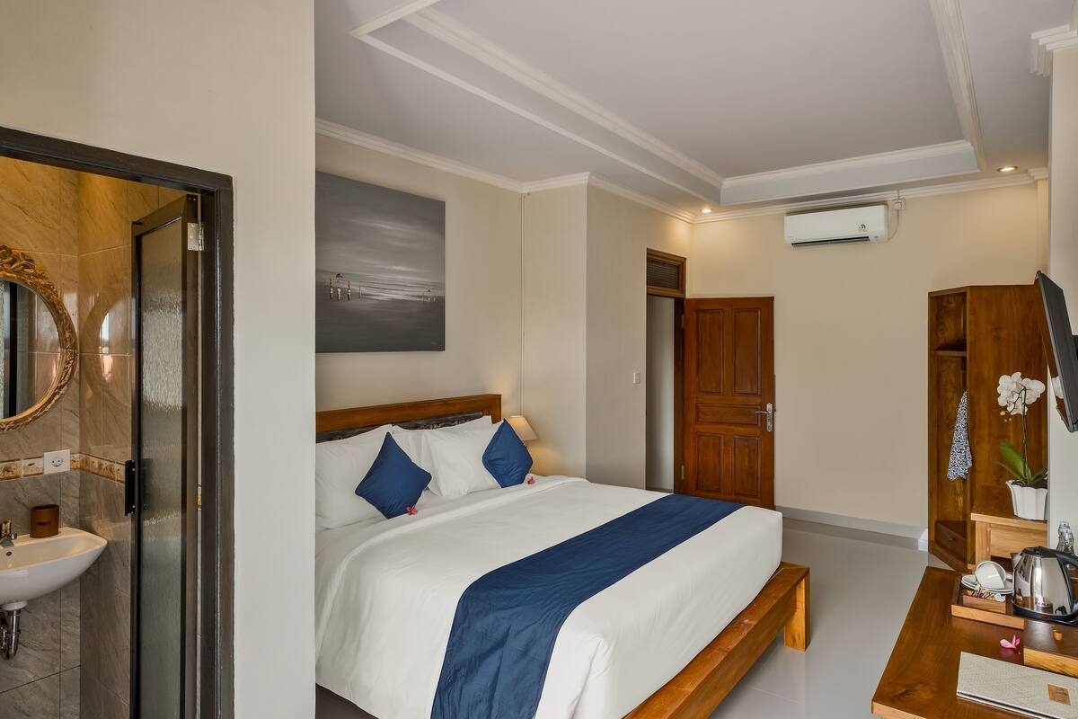 A hotel room with a bed, bedside table, mirror, and a view of the outside.