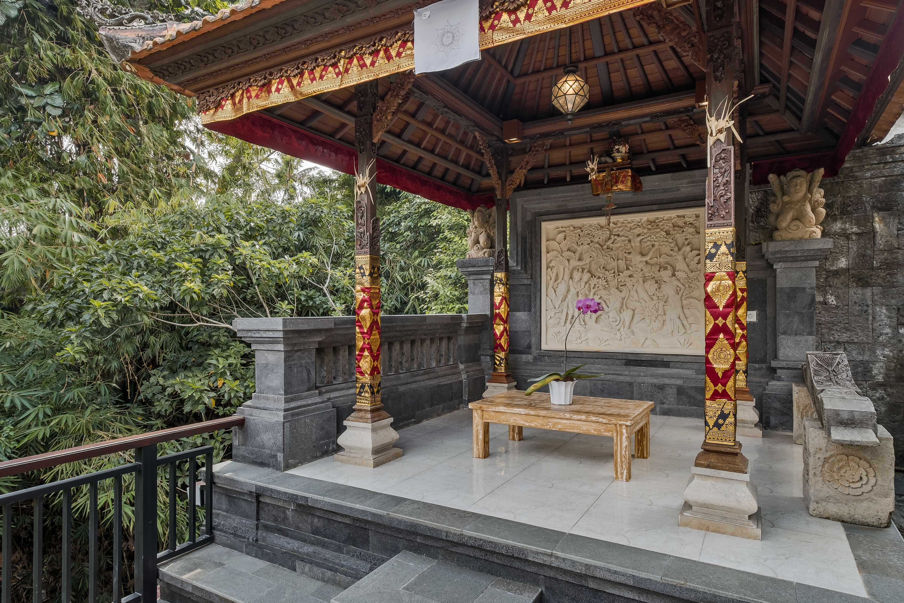 A traditional Balinese temple with ornate carvings, a wooden bench, and a statue.
