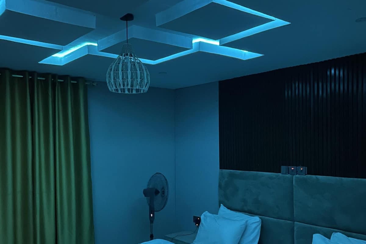 A modern bedroom with a bed, a ceiling light fixture, and a wall-mounted fan.