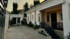 A residential street with white houses, paved walkways, and a clear sky. - 908 Apartments (Abuja)