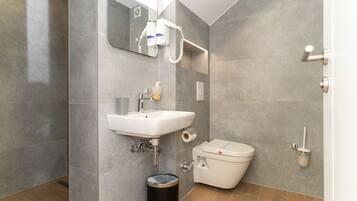 Een moderne badkamer met een wit wastafel, toilet en spiegel.