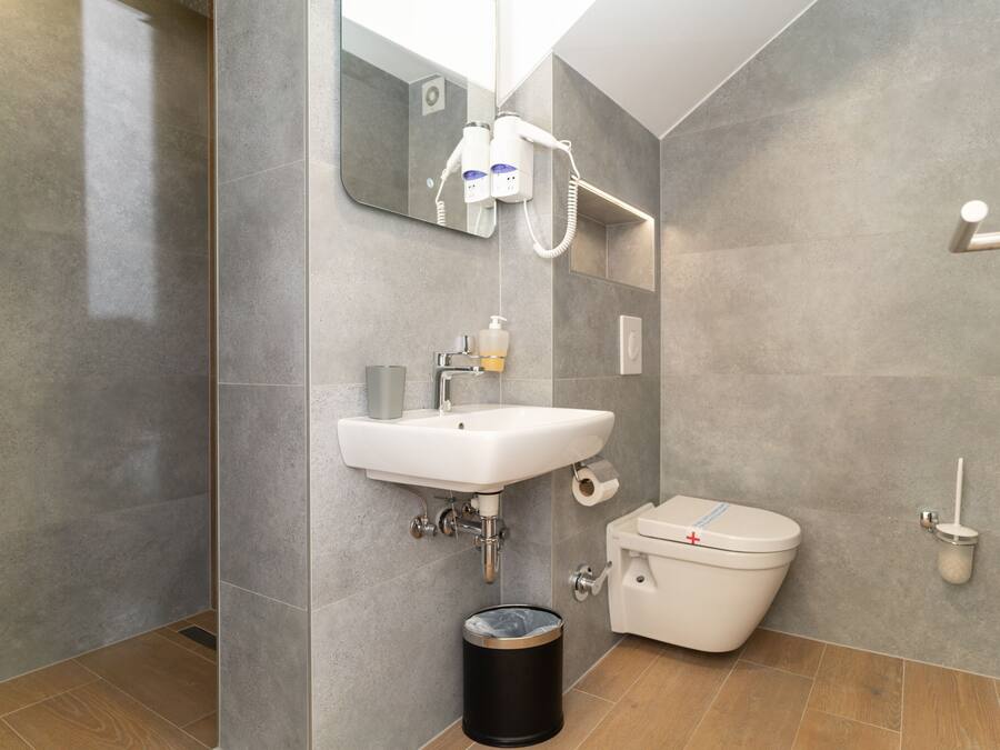 Een moderne badkamer met een wit wastafel, toilet en spiegel.
