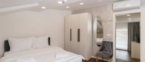 A modern bedroom with a large bed, a wardrobe, a chair, and an air conditioning unit.