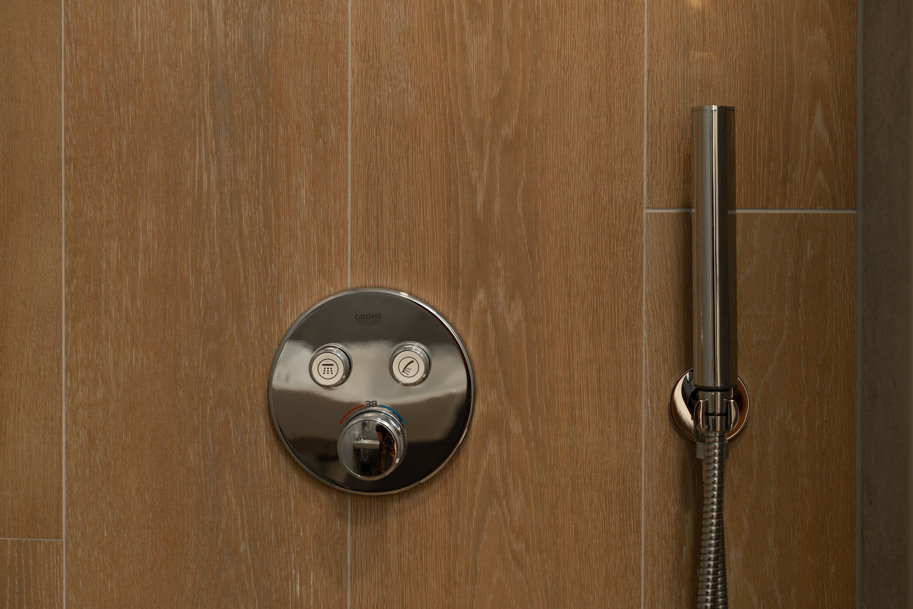 Un panneau de commande de douche moderne, doté d’un pommeau de douche à main.