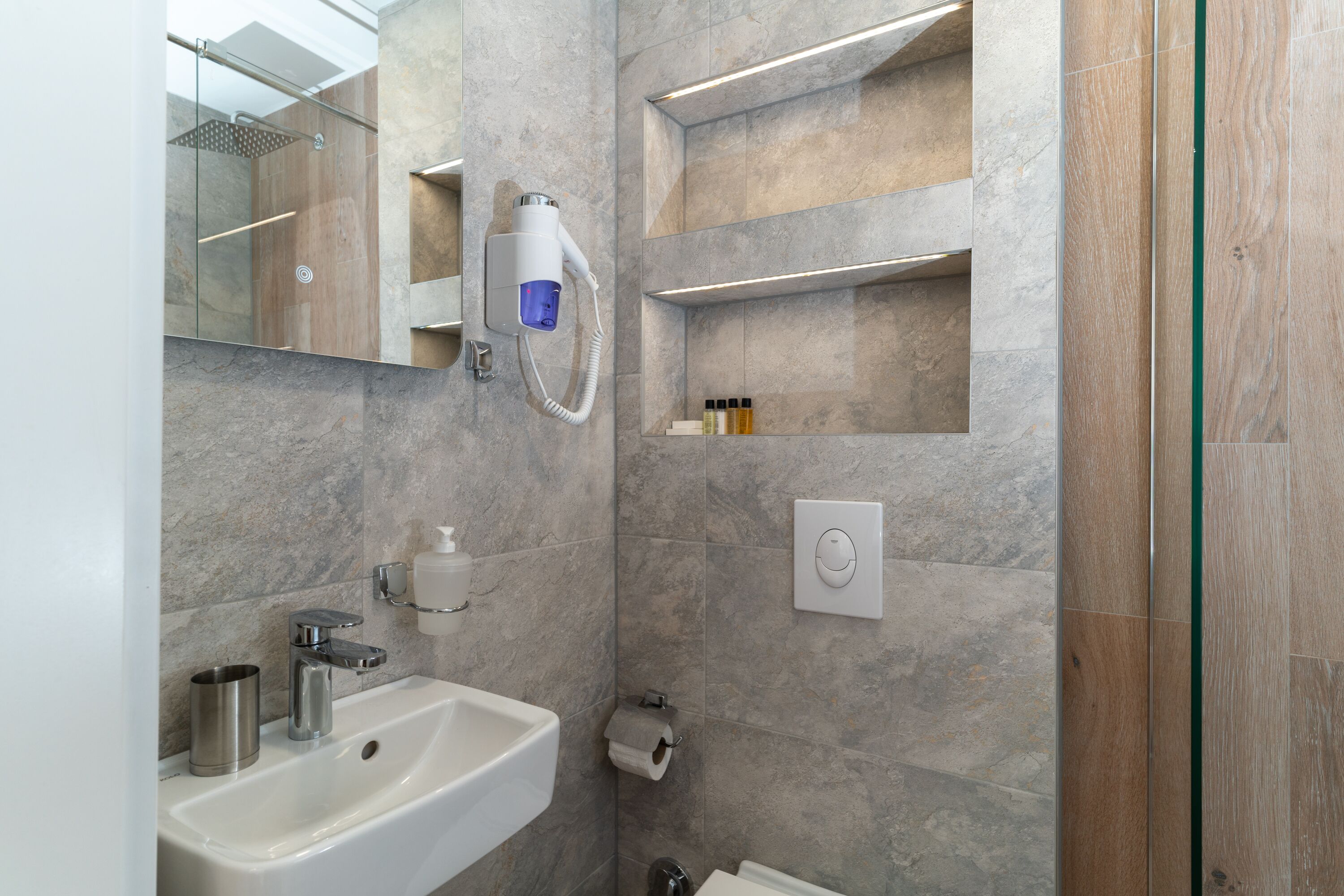 A modern bathroom with a white sink, a handheld showerhead, and a mirror.