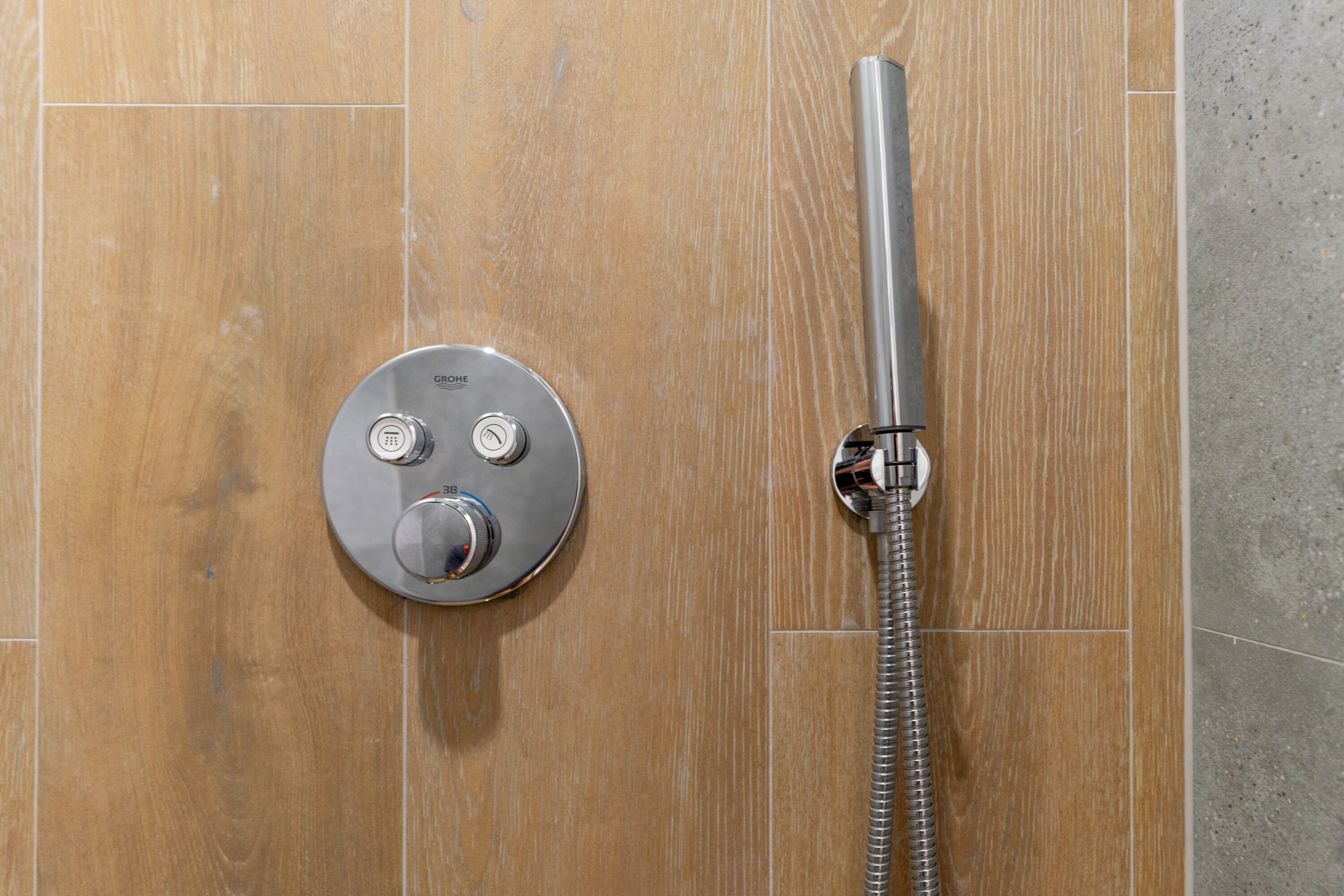 A modern shower with a control panel and a flexible hose.