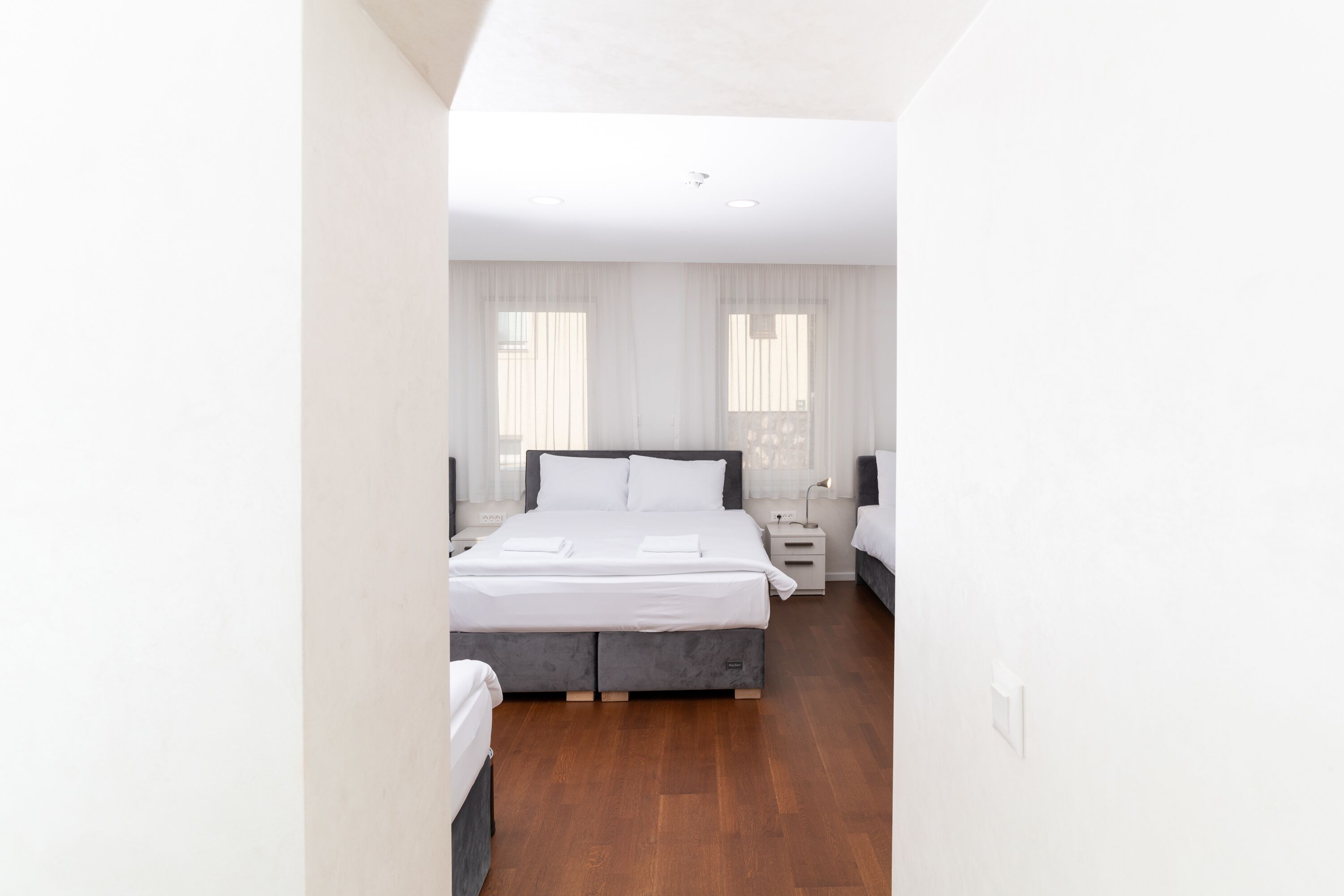 Une chambre d’hôtel moderne avec un grand lit, des tables de chevet et un plancher en bois.