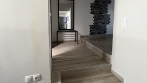 A staircase with wooden steps leading to a room with a mirror and a wall with a textured pattern.