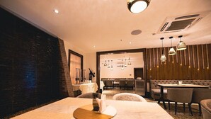 A modern hotel room with a large bed, a dining area with a round table, and a seating area with a sofa and chairs. - Meethaq Hotels Jabi (Abuja)
