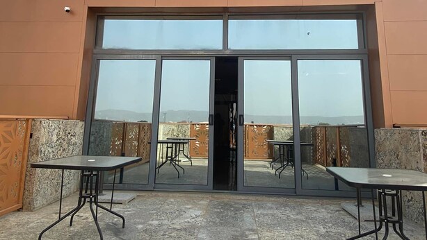The exterior of Meethao Hotels with a large entrance, two tables, and a view of the surrounding area. - Meethaq Hotels Jabi (Abuja)