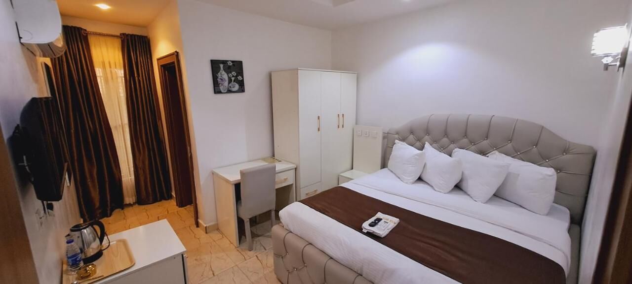 A hotel room with a bed, a desk, a wardrobe, and a shower area.