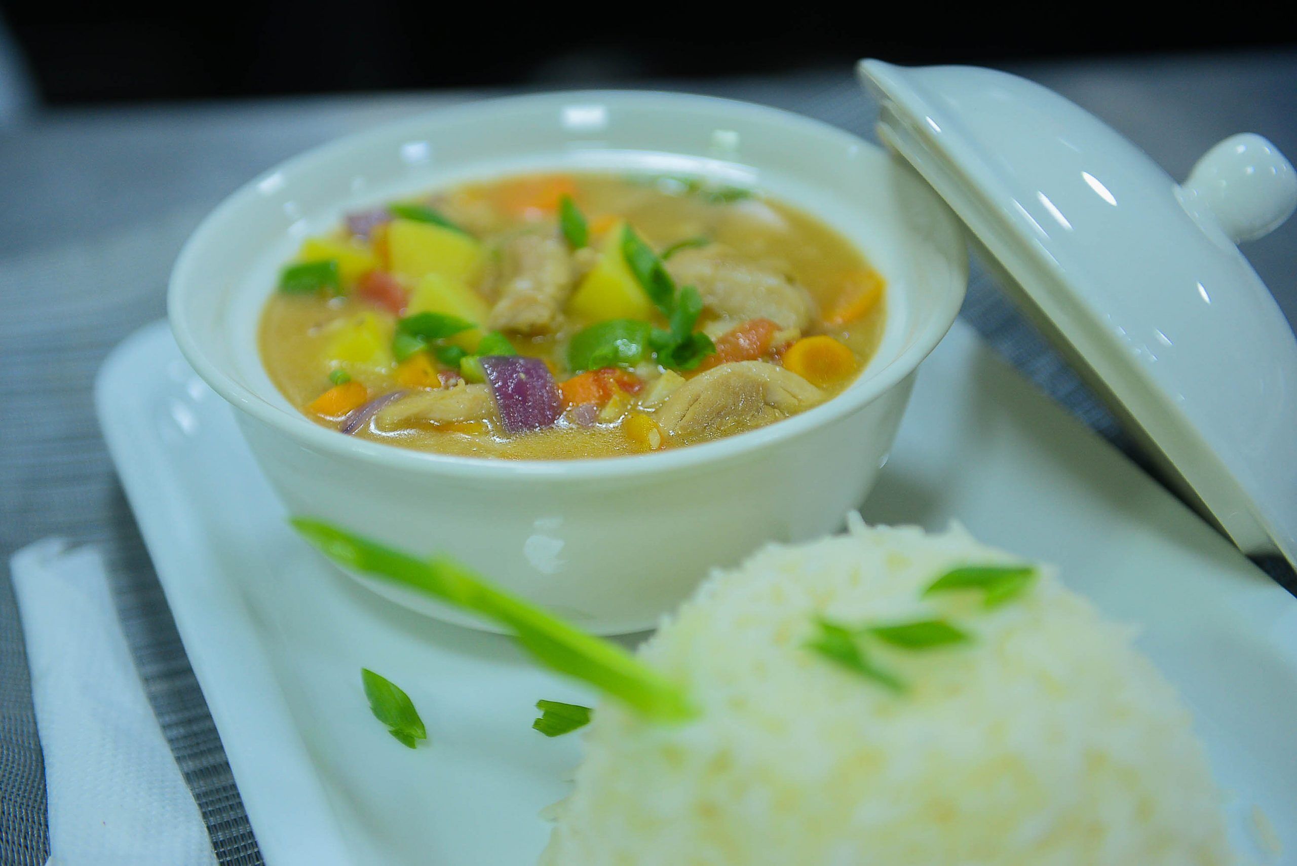 Un bol de soupe avec du riz, servi dans une assiette blanche.