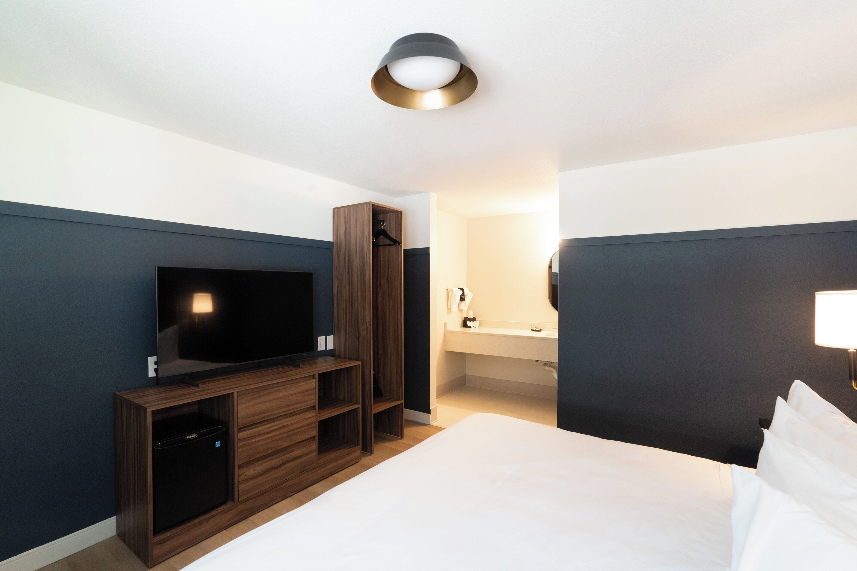 Ein Hotelzimmer mit Bett, Fernseher, Kleiderschrank und Badezimmer.
