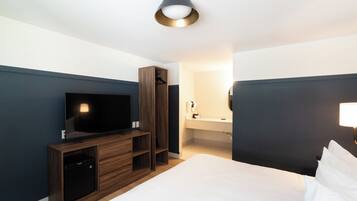 Ein Hotelzimmer mit Bett, Fernseher, Kleiderschrank und Badezimmer.