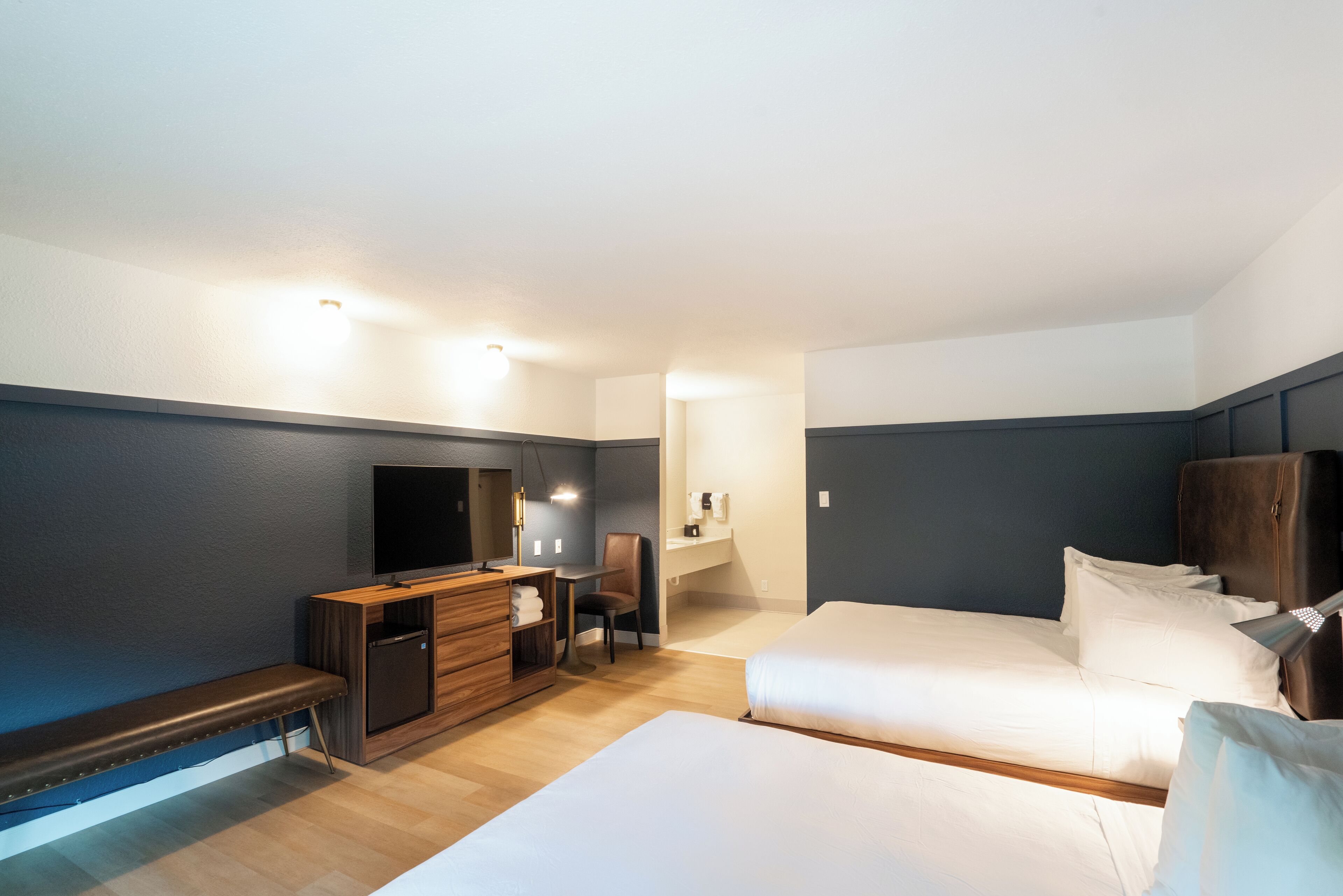 A hotel room with a bed, a desk, a chair, a TV, and a wardrobe.