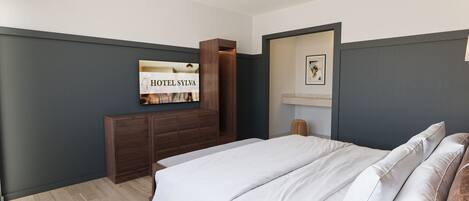 Un dormitorio con cama, armario de madera, espejo y un cuadro enmarcado en la pared.