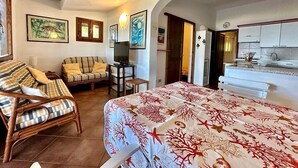 Une pièce confortable avec un lit, deux canapés, une petite table et un coin cuisine.