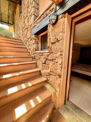 A stone staircase leading to a room with a bed and a window. - Residence Domos De Rocca (San Teodoro)