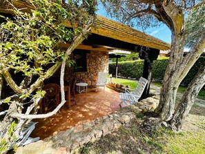 A covered patio with stone walls, outdoor seating, and a pergola. - Residence Domos De Rocca (San Teodoro)
